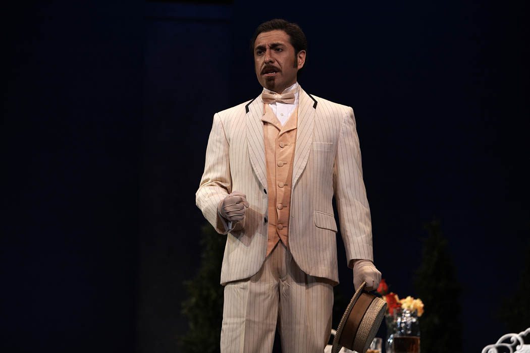 Marcos Vigil, Tenor, wearing a light peach colored suit with pinstripes, a peach colored waistcoat with a matching bow tie, and light colored gloves.